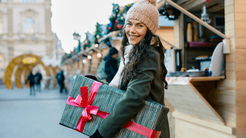 Nasmijana djevojka nosi poklon za Božić